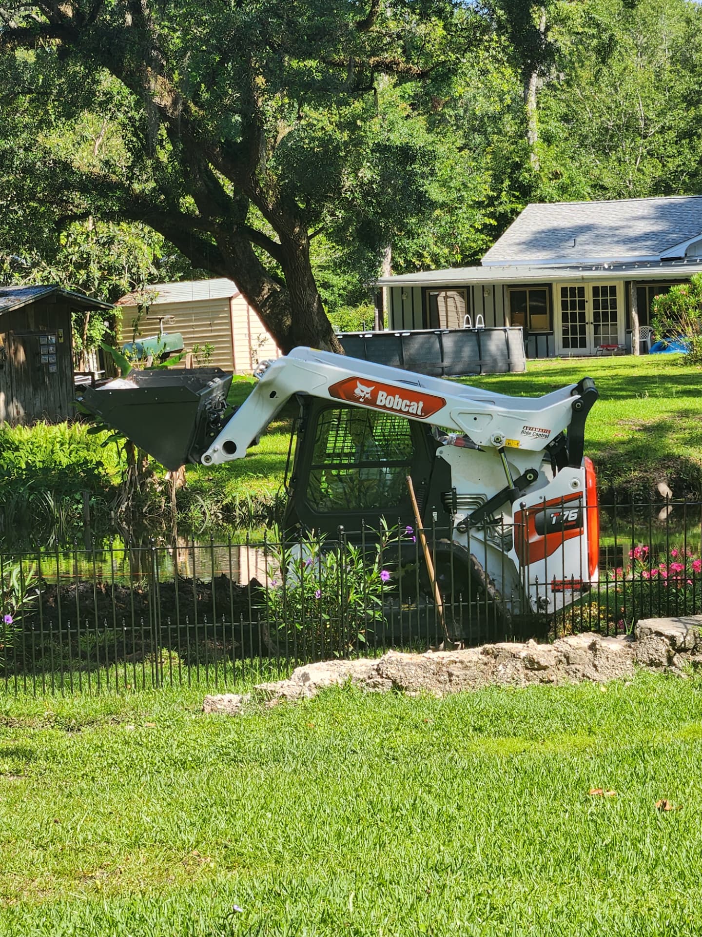 Compact track loader clearing brush along a pond bank
